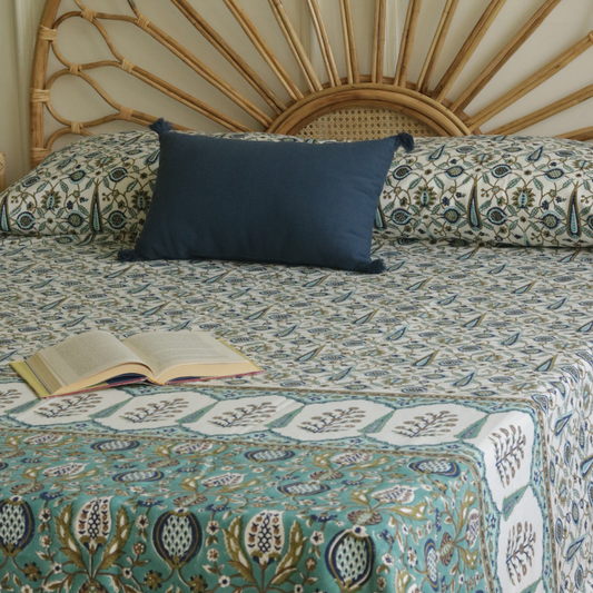Teal and blue bed cover with scattered leaf and teardrop motifs