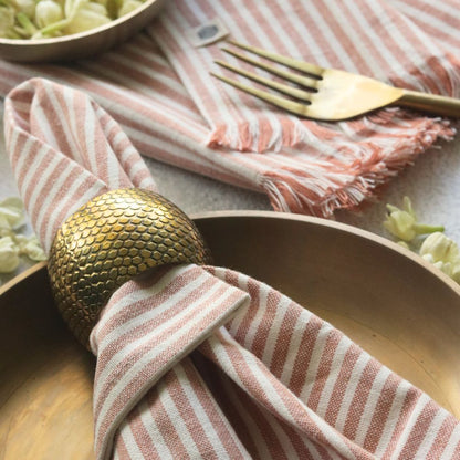 Dusty rose striped cotton napkin with fringe, folded on table setting