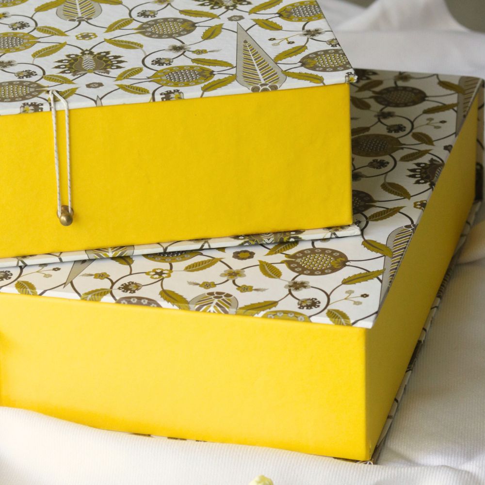 Stacked small patterned hamper gift boxes with yellow sides and clasp hardware
