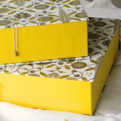 Stacked small patterned hamper gift boxes with yellow sides and clasp hardware