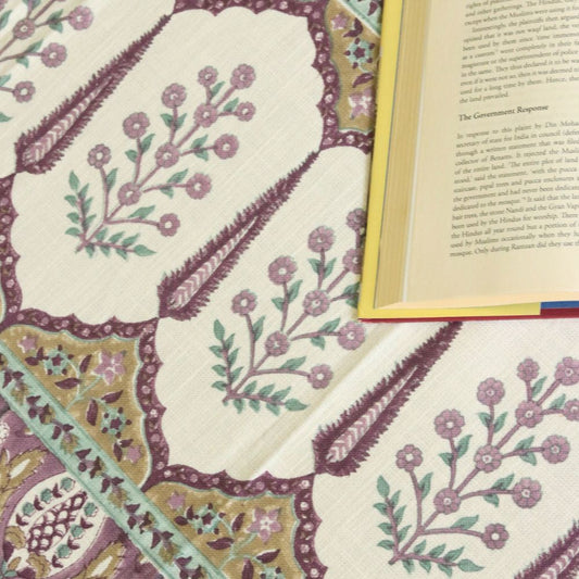 Fabric close-up of white ground with mauve floral medallions and decorative border