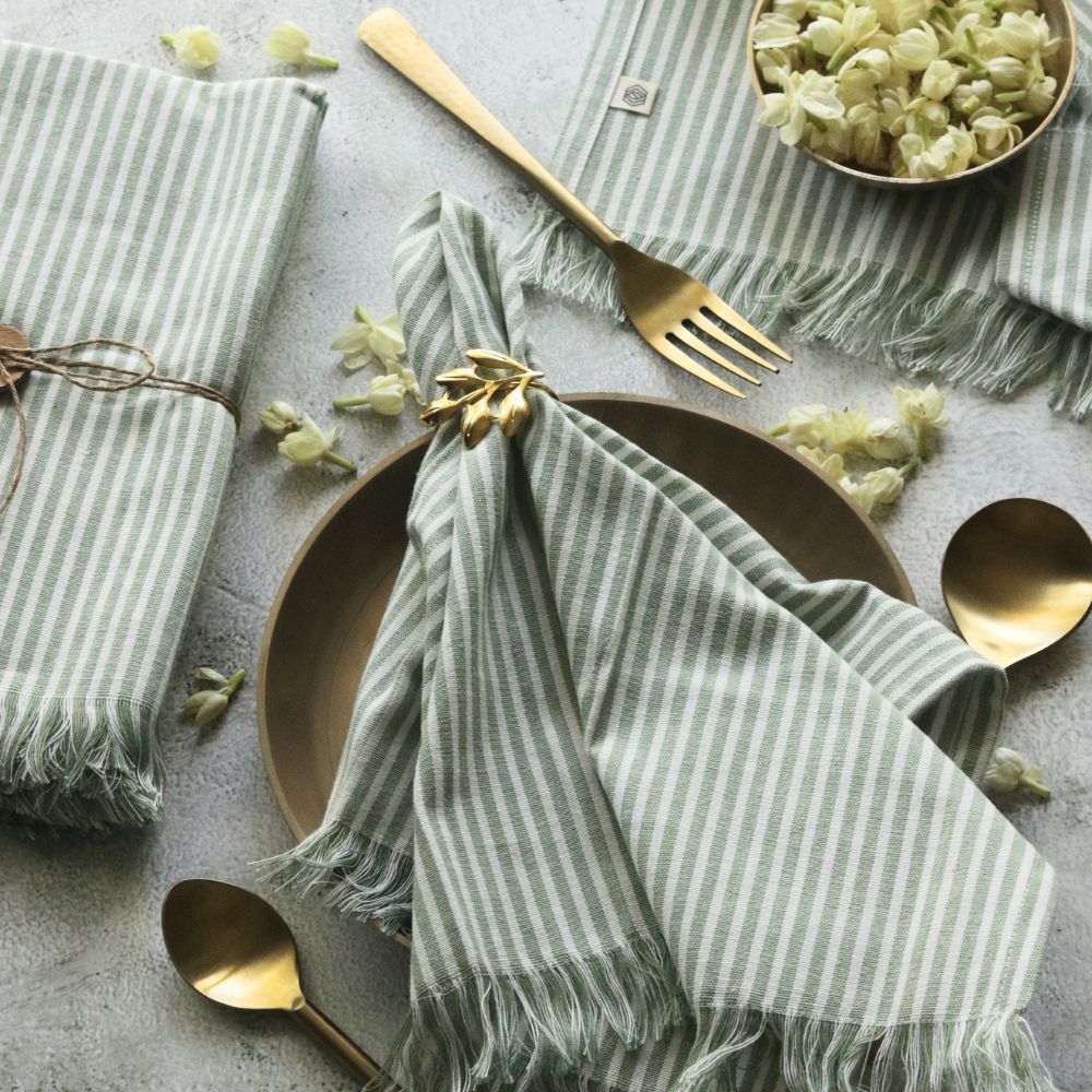 Sage green striped cotton napkin with fringed border and centered bow fold