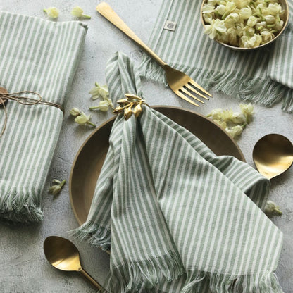 Sage green striped cotton napkin with fringed border and centered bow fold