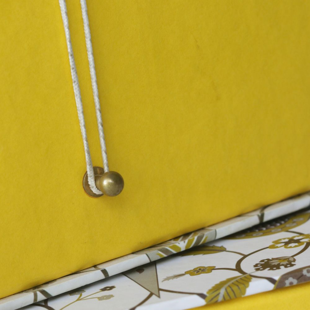 Yellow hamper box with hanging drawcord and patterned trim along the bottom edge