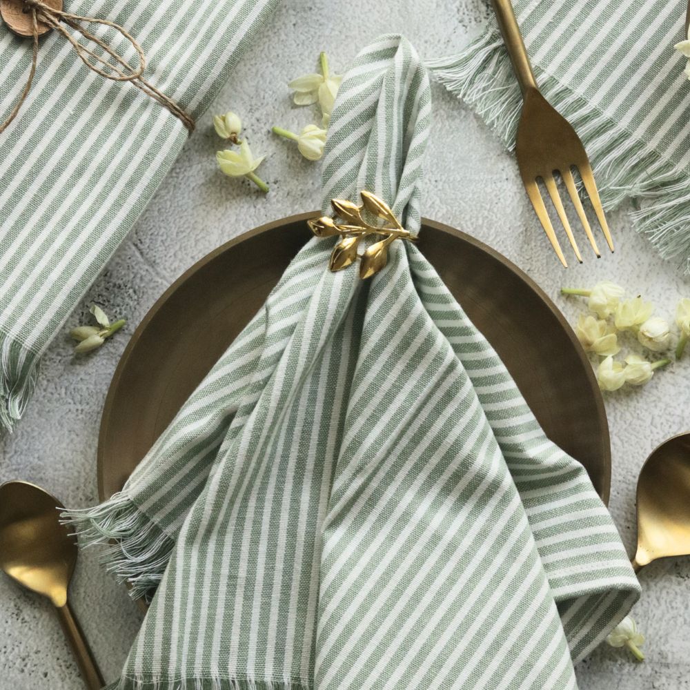 Sage green striped cotton napkin with fringed edges and small centered bow