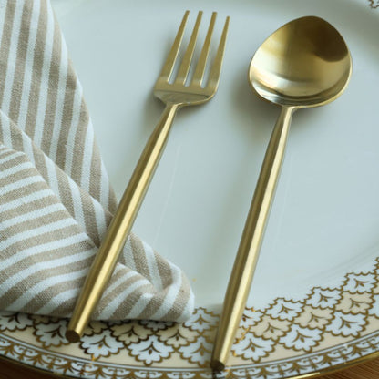 Matte gold dinner spoon and fork shown close up with four-tine fork