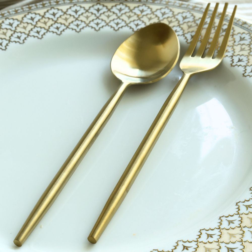 Matte gold dinner spoon and fork with slim handles on a plate
