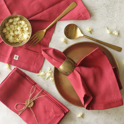 Red cotton table napkins, folded with stitched edges and small woven label