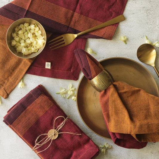 Cotton table napkin set in rust-orange and burgundy stripes, folded with fringe