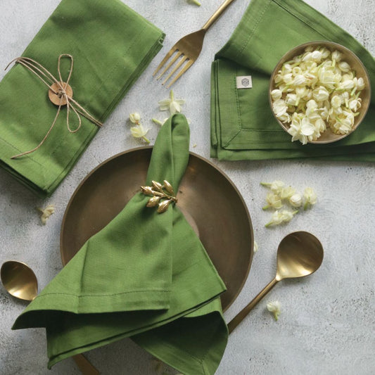 Green cotton table napkins, neatly folded with stitched edges and tied ribbon detail