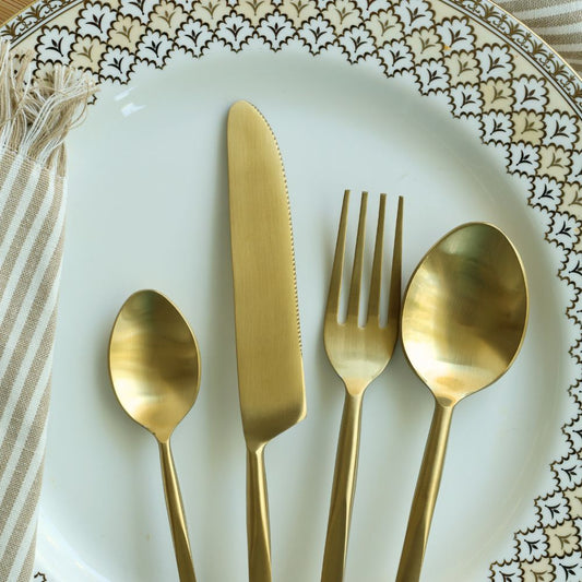 Matte gold cutlery set with dinner knife, fork, tablespoon, and teaspoon