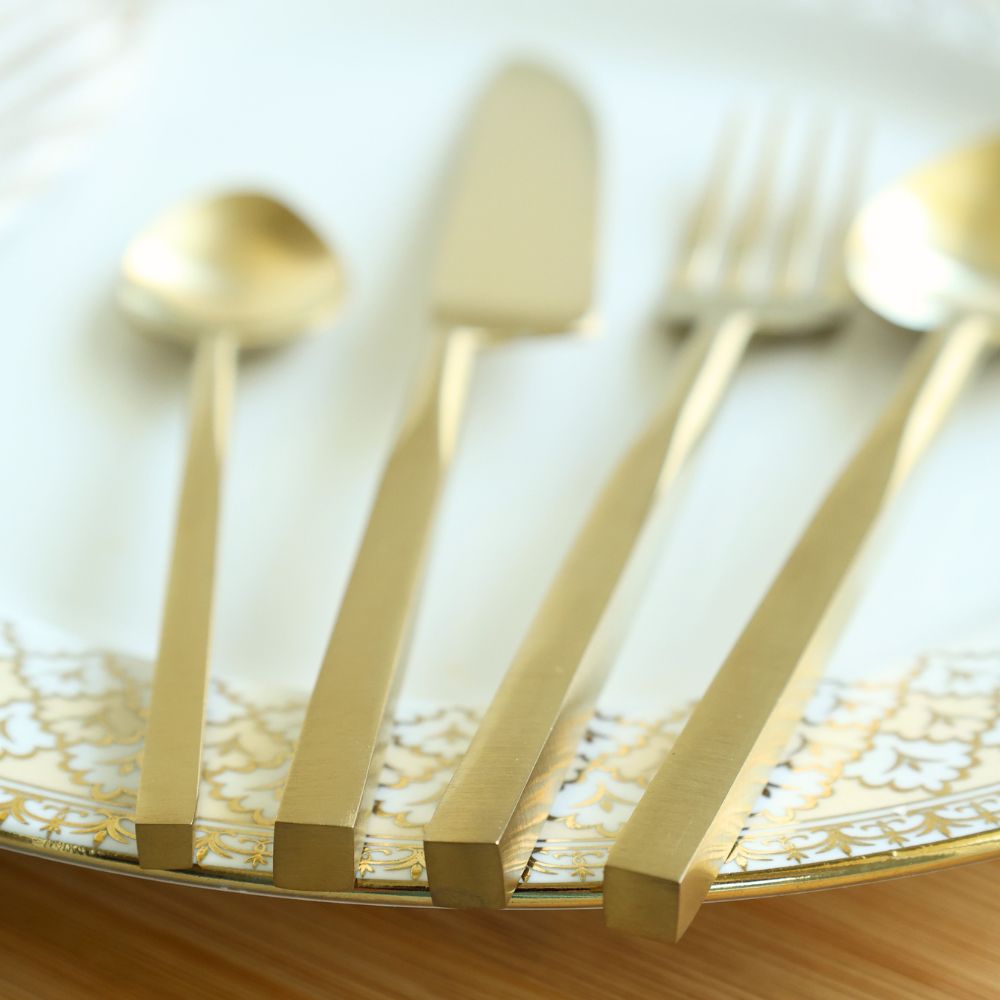 Matte gold cutlery set viewed close up, showing the flat-ended handles