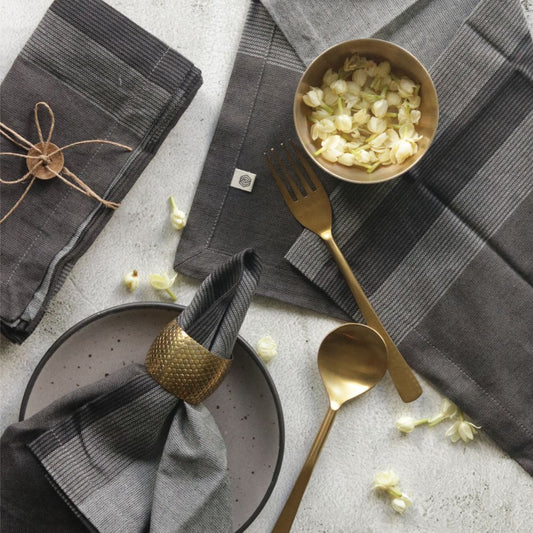 Gray cotton table napkins with plaid pattern, folded and arranged with dining utensils