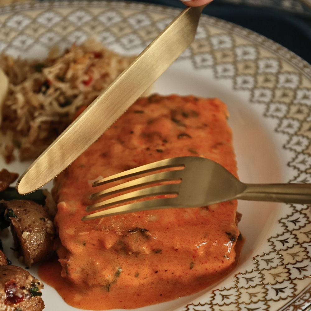 Matte gold knife and fork shown cutting into food