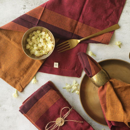 Rust-orange and burgundy striped cotton napkins, one folded with corner label
