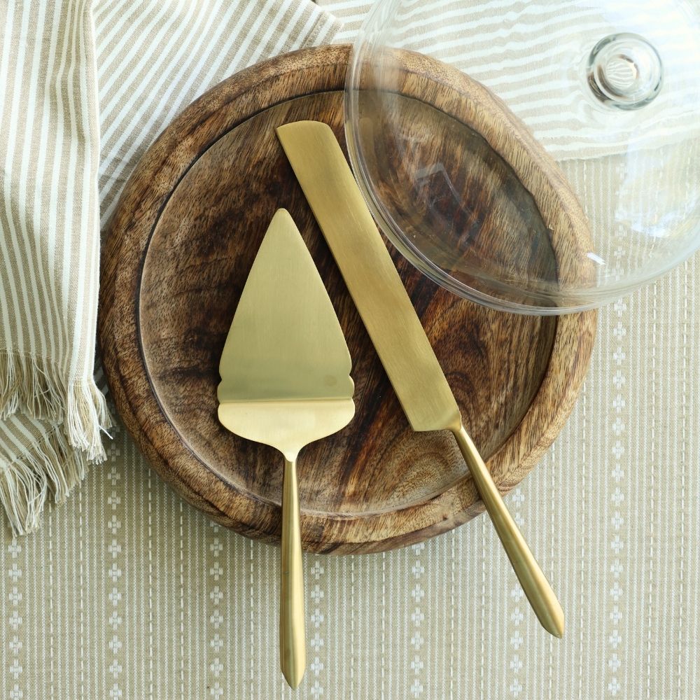 Matte gold pie cutter and server set of 2 on a wooden serving board.