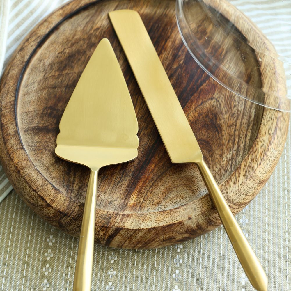 Close view of matte gold pie cutter and server with flat, broad blades.