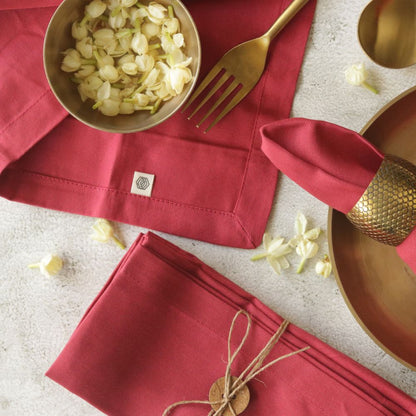 Red cotton table napkin with square tag, folded and laid flat