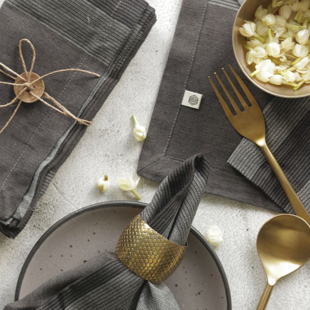 Gray cotton plaid napkins, folded and stacked with a napkin ring on a plate