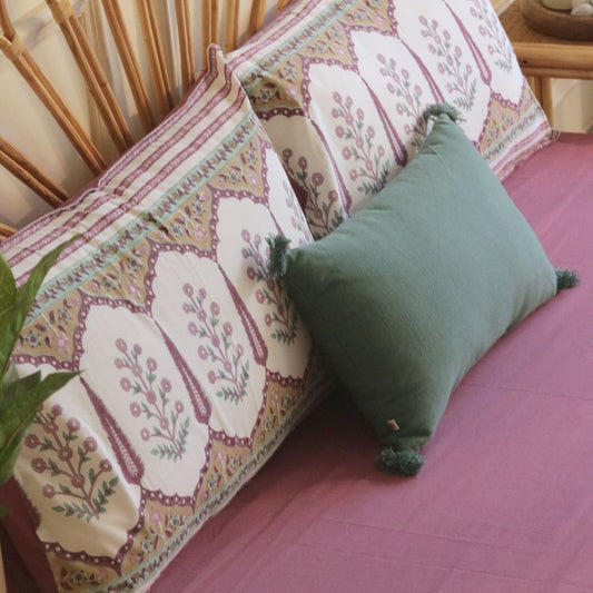 Mauve bedsheet corner section on bed with smooth fabric and stitched edge