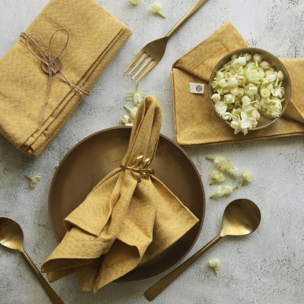 Mustard yellow cotton napkins, stacked and fan-folded with bow ties
