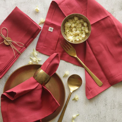 Red cotton napkins, neatly folded with stitched corners and small woven label