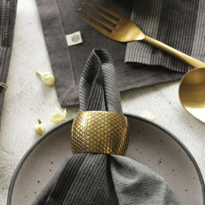 Gray cotton plaid napkin, folded into a ring atop a dark plate centerpiece