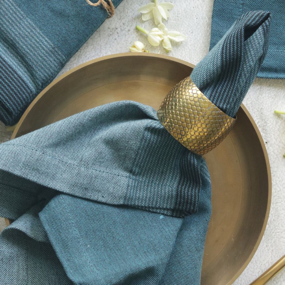 Aegean blue cotton napkin with stitched edge, folded into a ringed shape