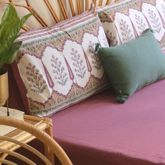 Mauve bedsheet stretched across bed with subtle wrinkles and clean edge stitching