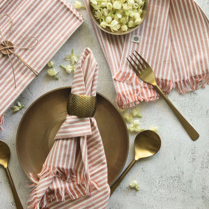 Dusty rose striped cotton napkins with fringed ends, wrapped around napkin holder