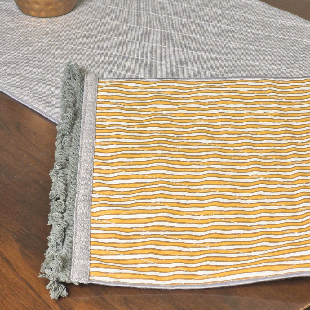 Close-up of an ochre and white striped 4 seater reversible runner edge with grey fringed tassels.