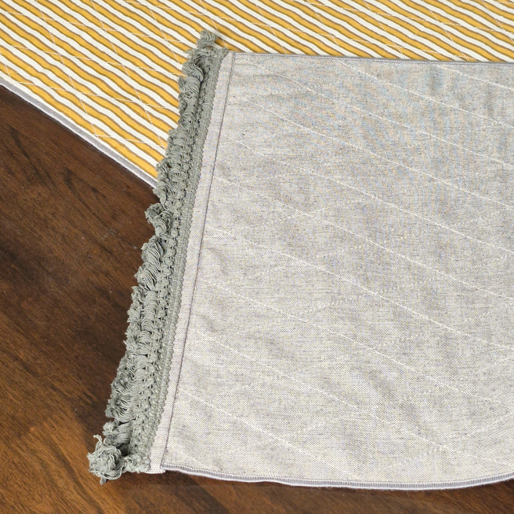 Close-up of the grey textured corner and fringed tassels on a 4 seater reversible runner.