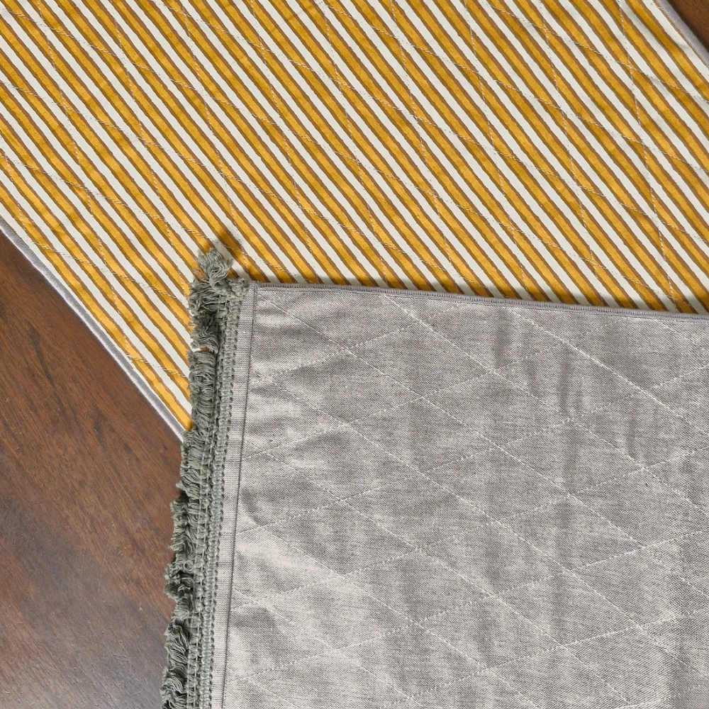 Flat lay of an ochre striped runner with a grey textured reversible side and fringed border.