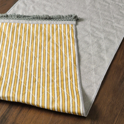 Folded ochre striped 6 seater reversible runner showing its solid grey textured underside and grey fringe.