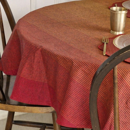 Round table with a red and brown checkered tablecloth, gold cup, and silverware.