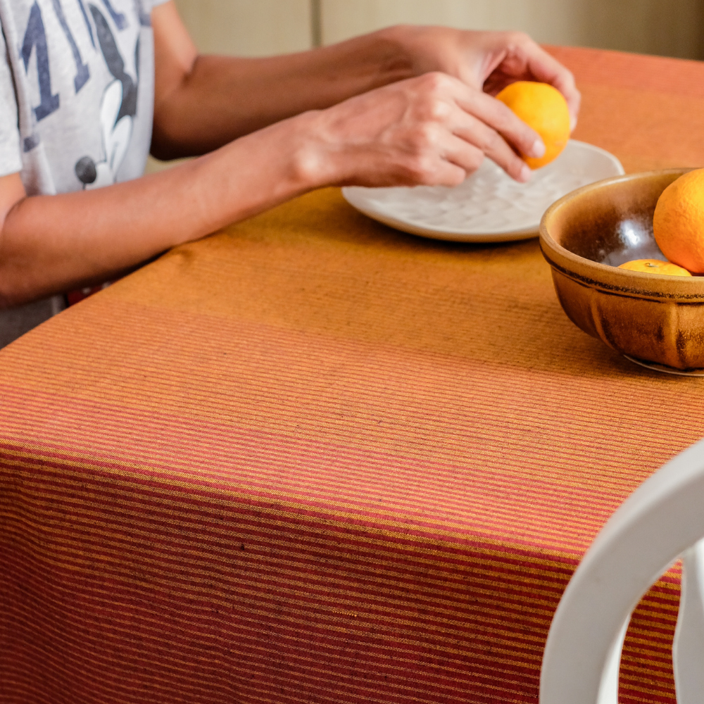 Dining table with a red tablecloth and woman peeling orange