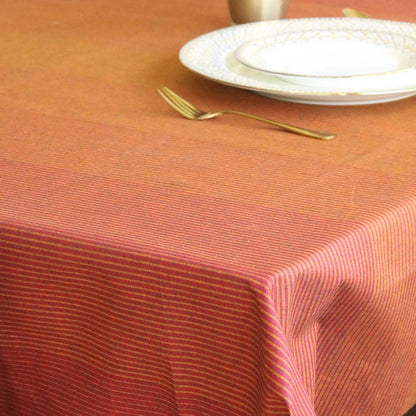 Table setting with a red and white striped tablecloth, plates, and a fork on a wooden surface.