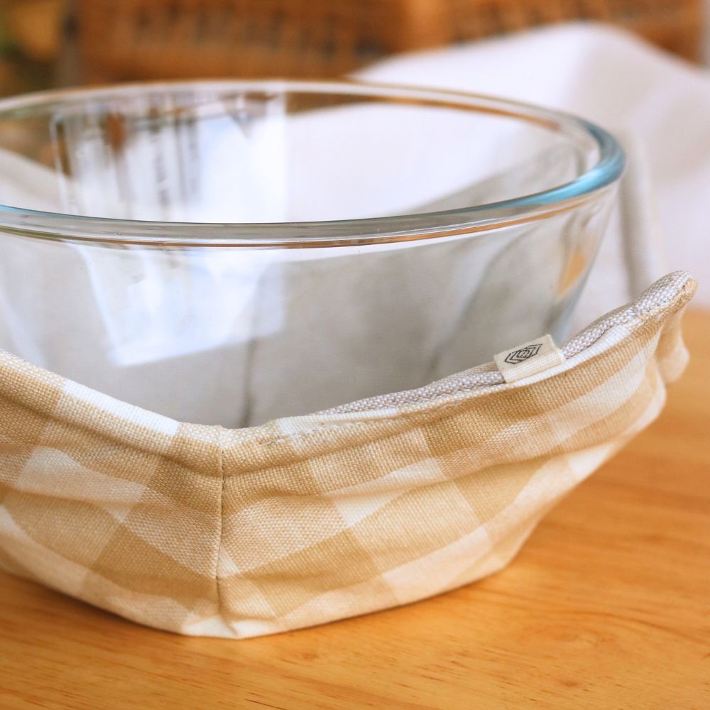 Reversible bowl-style pot holder with beige check lining, fitted around a glass bowl