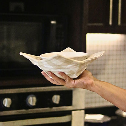 Bowl-style reversible pot holder in beige check fabric, held open for cookware